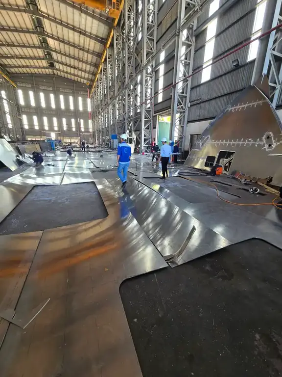 Workshop floor with curved aluminum parts and workers